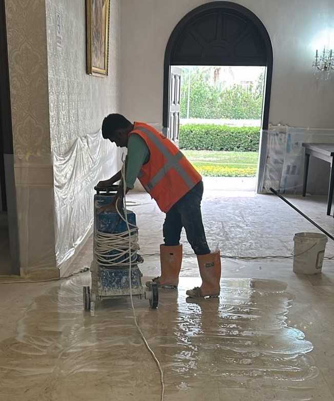 فني صيانة يصقل أرضية رخامية في فيلا كويتية